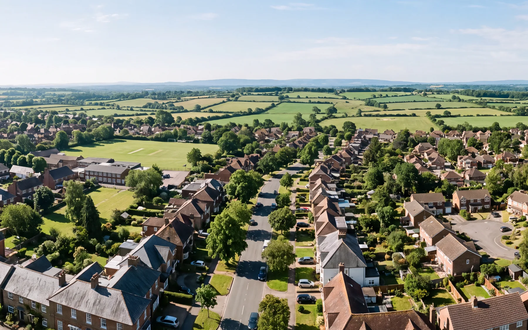 An aerial view over Slough and the surrounding Home Counties rooftops toward open green belt farmland