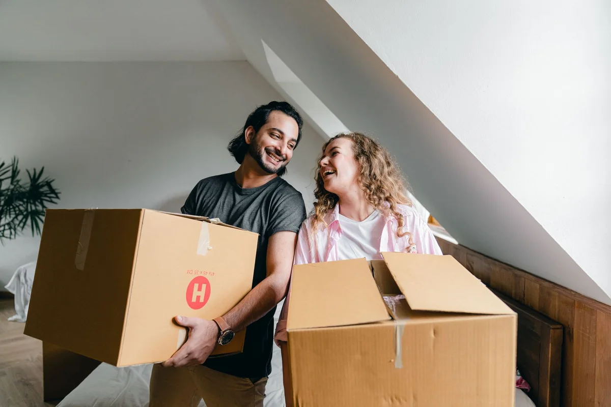 A couple laughing together while unpacking moving boxes.
