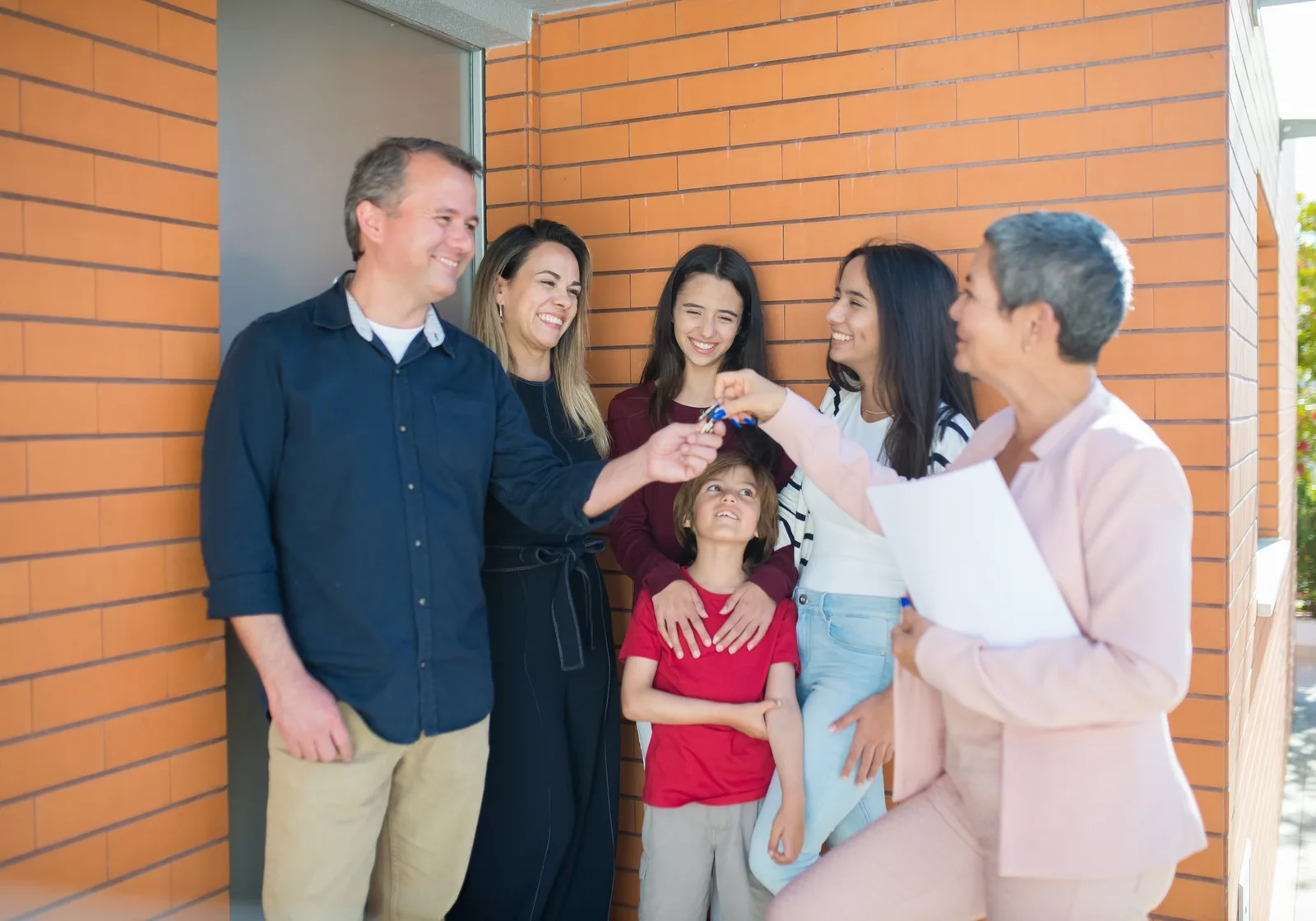 A happy family receiving the keys to a new home outside the property.