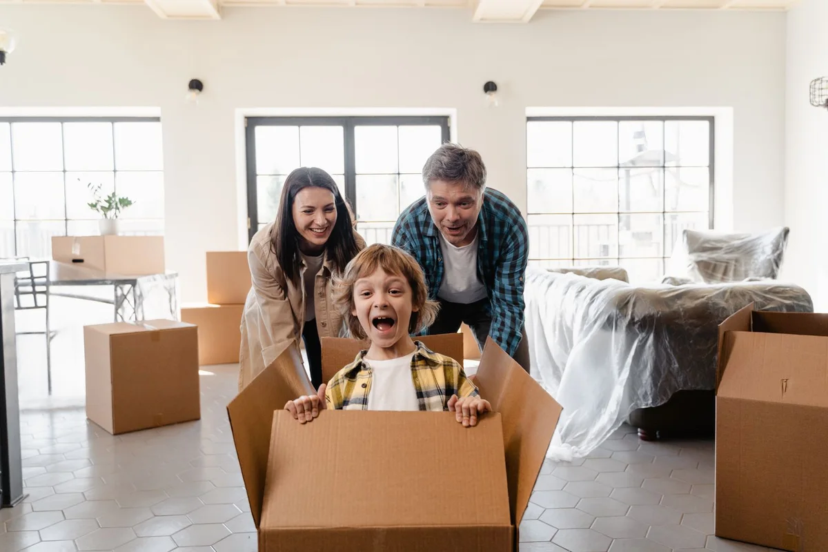 A family laughing together among moving boxes in a bright home.