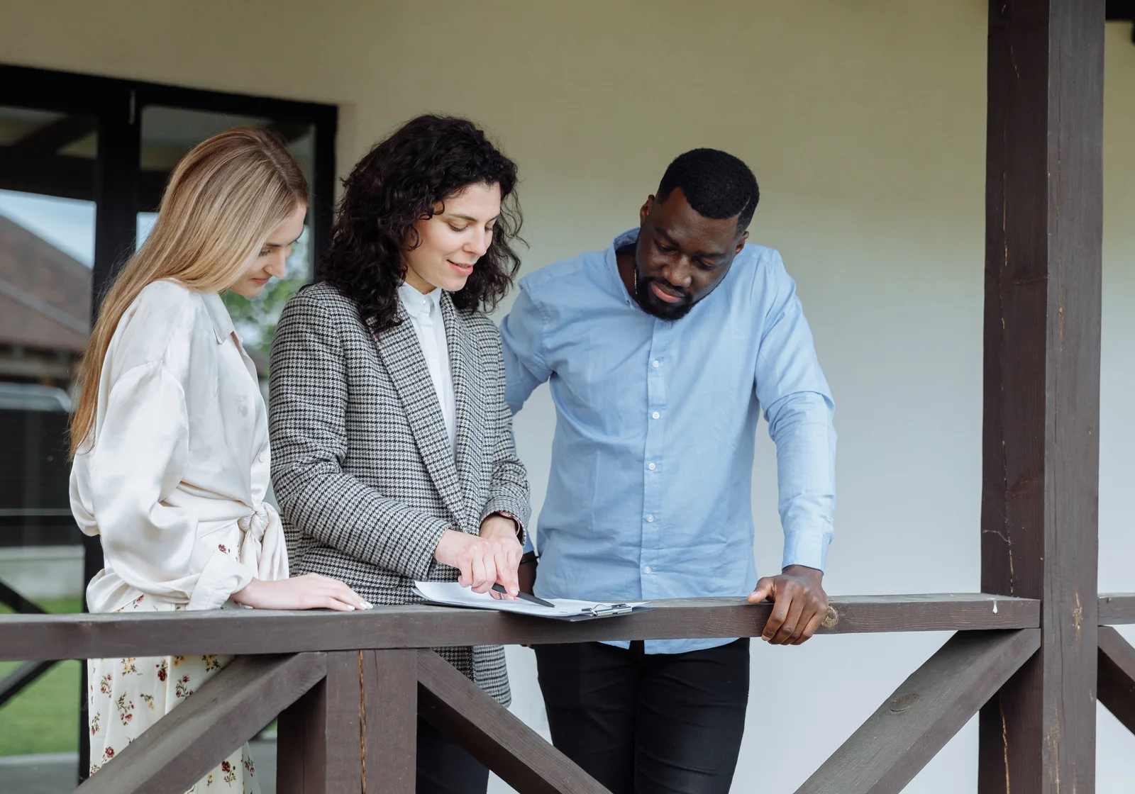 A property adviser discussing paperwork with two people outside a home.