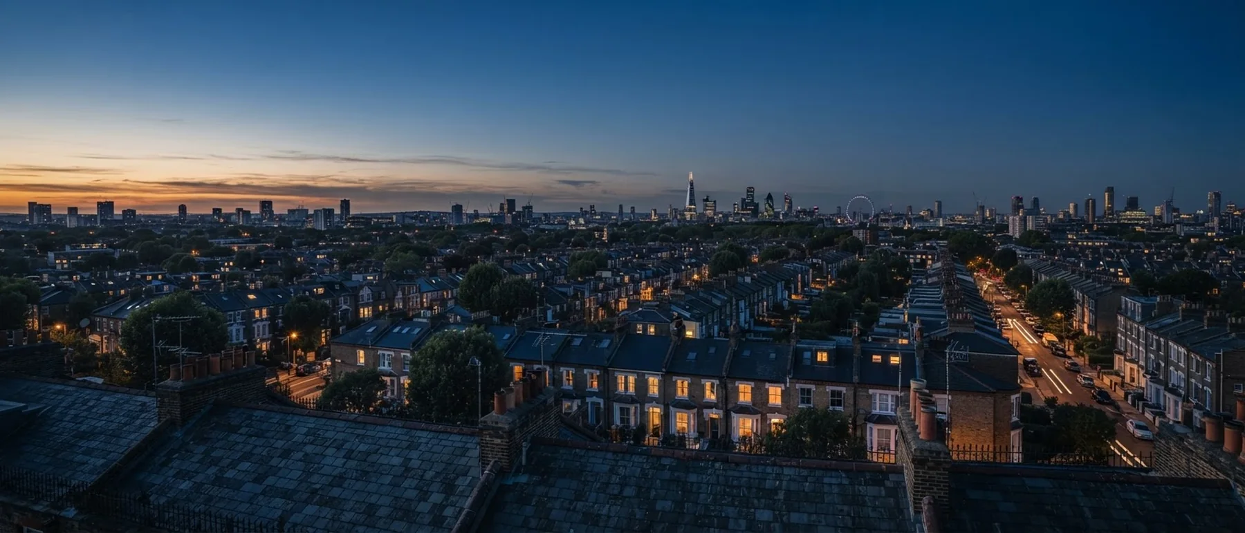 London terraced rooftops at blue hour, windows lit warm amber toward a distant skyline